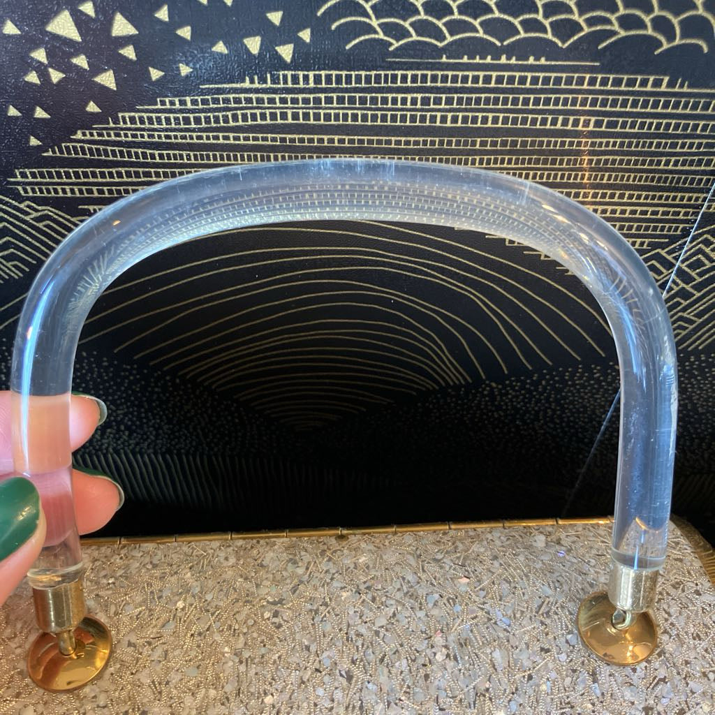 Clear plastic handle with gold accents held against a textured black background