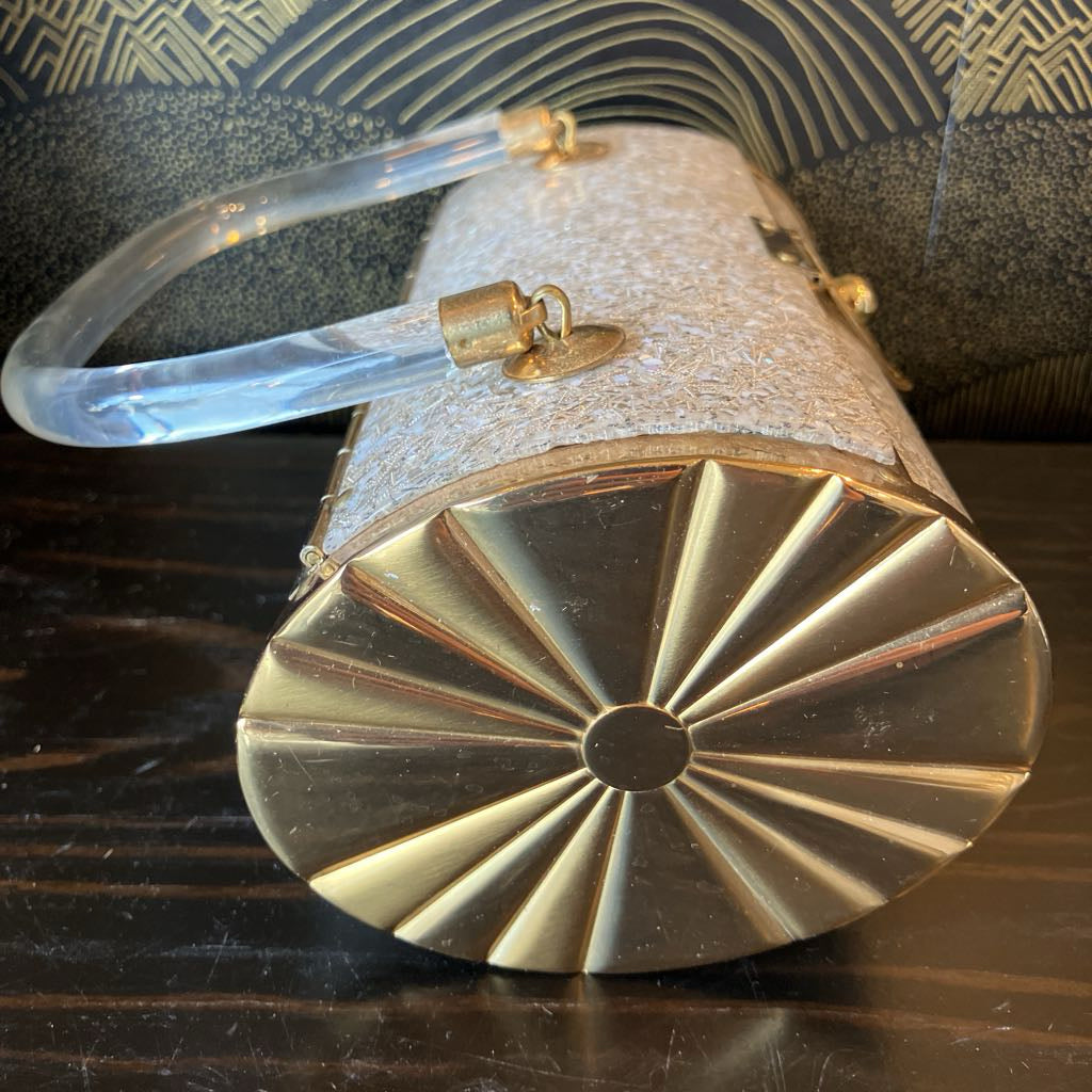 Gold and clear handbag with decorative handle on a dark surface