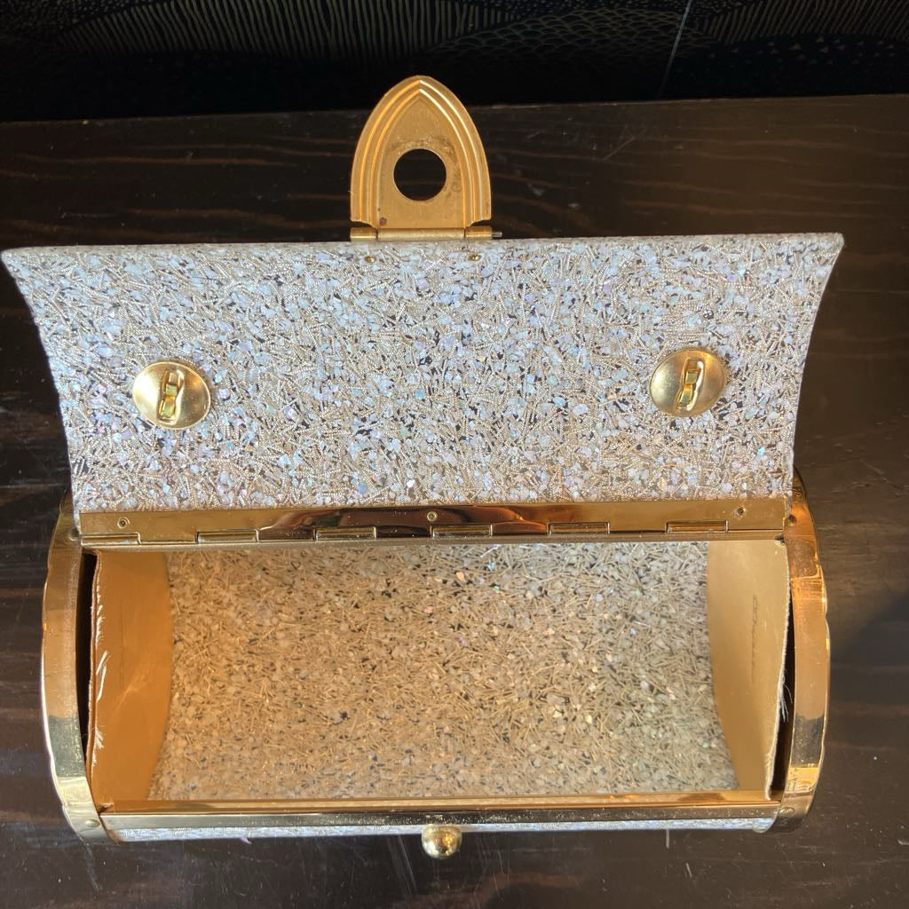 Gold and silver glittery clutch bag on a dark surface
