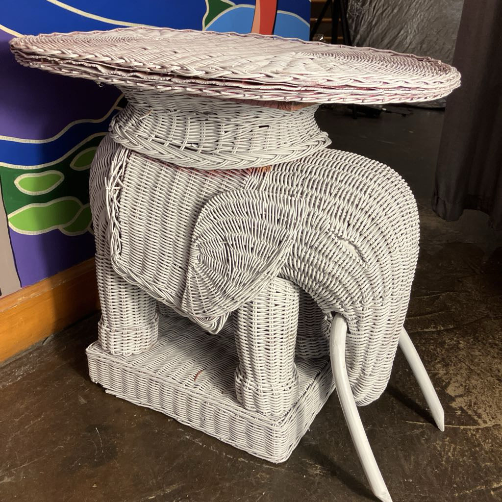 Wicker elephant side table with round top in a room setting