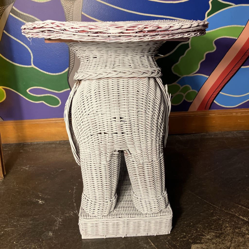 Back of a white wicker elephant with a decorative top against a colorful wall.