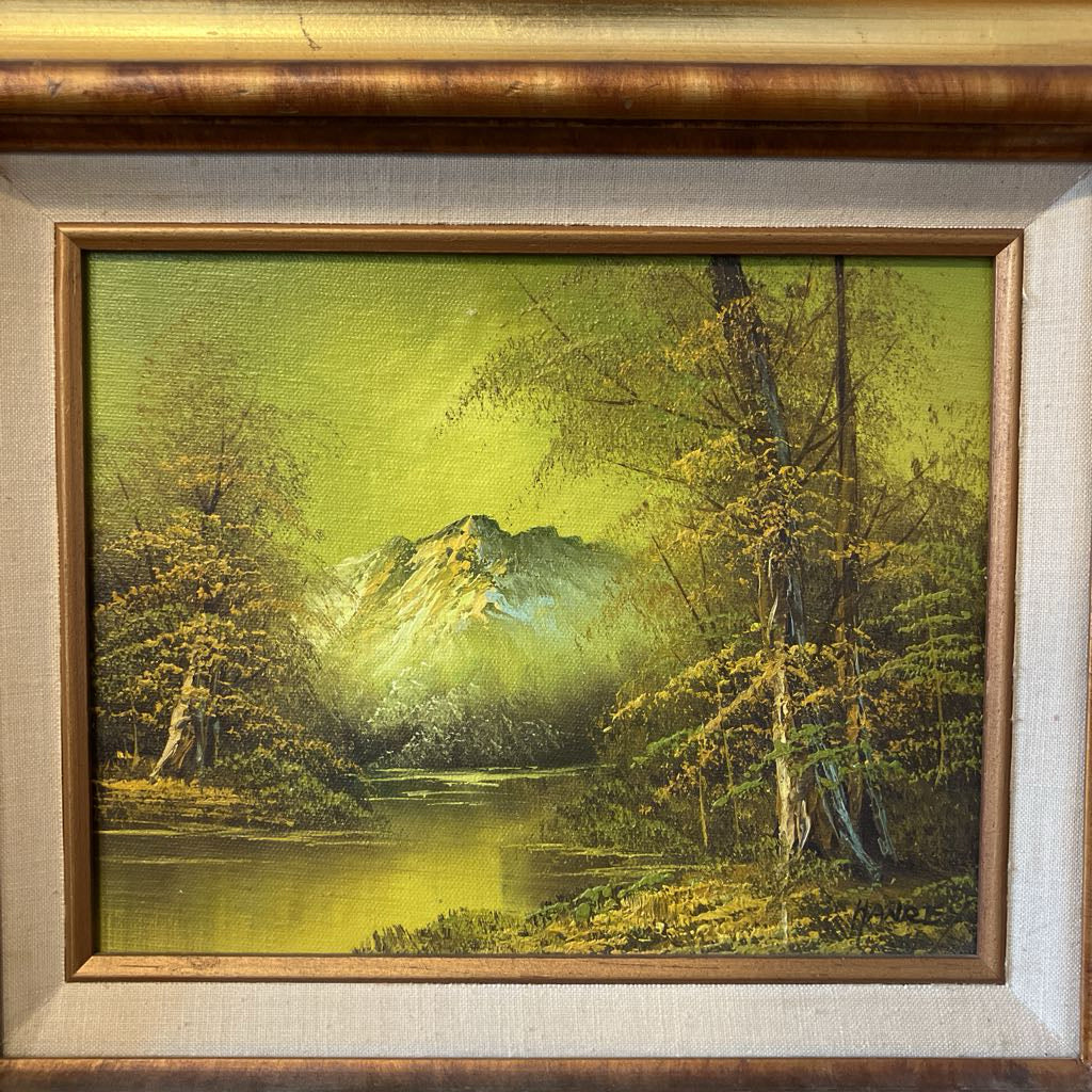 Framed painting of a mountain landscape with trees and water.