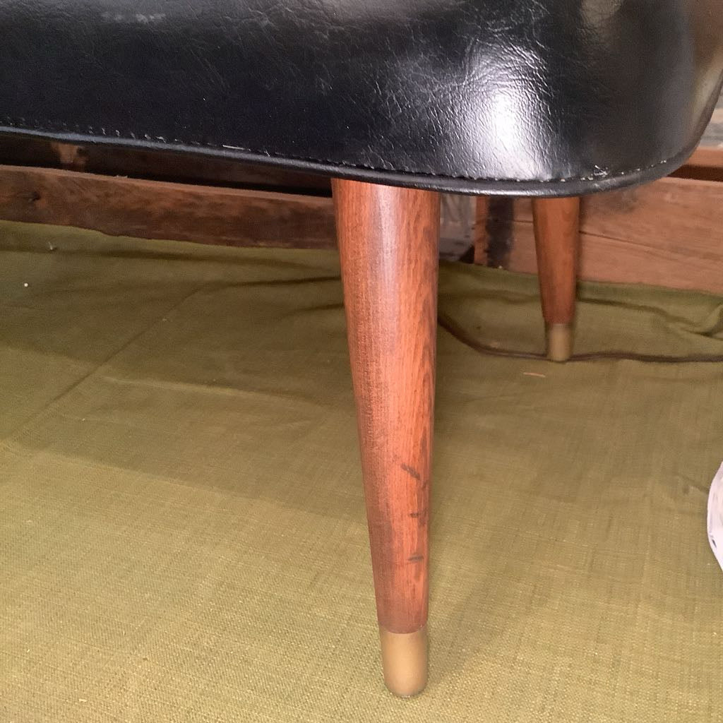 Close-up of a chair with wooden legs on a green fabric background