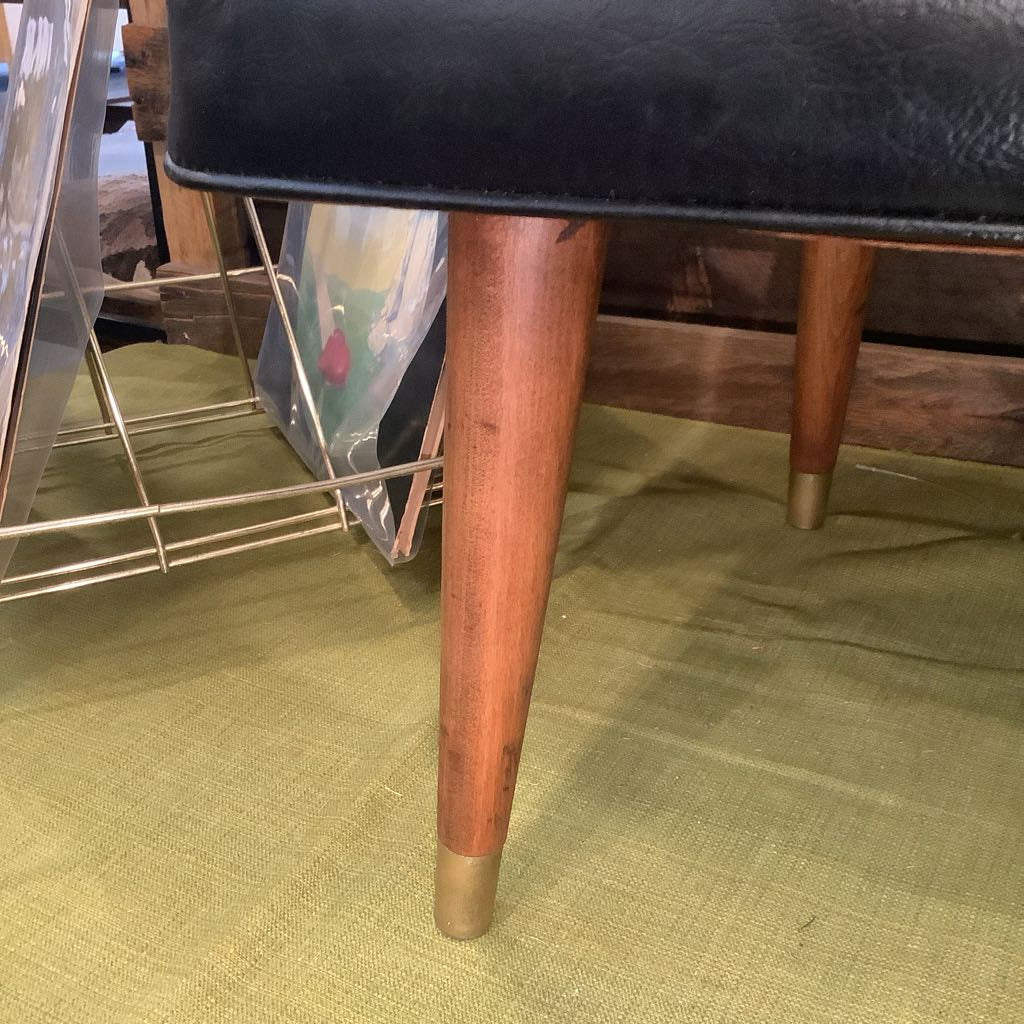 Wooden chair leg on a green carpet with a blurred background