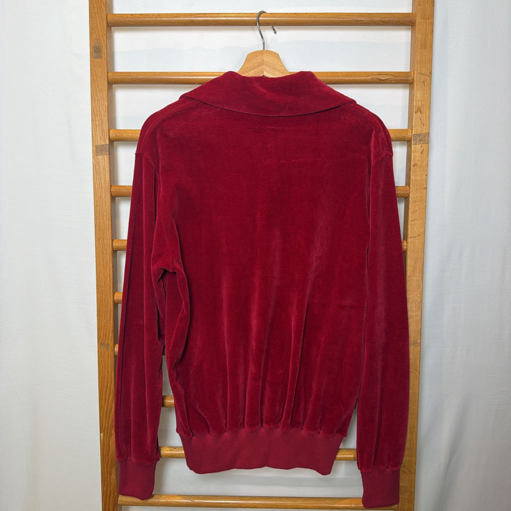 A red velour sweater on a wooden rack. 