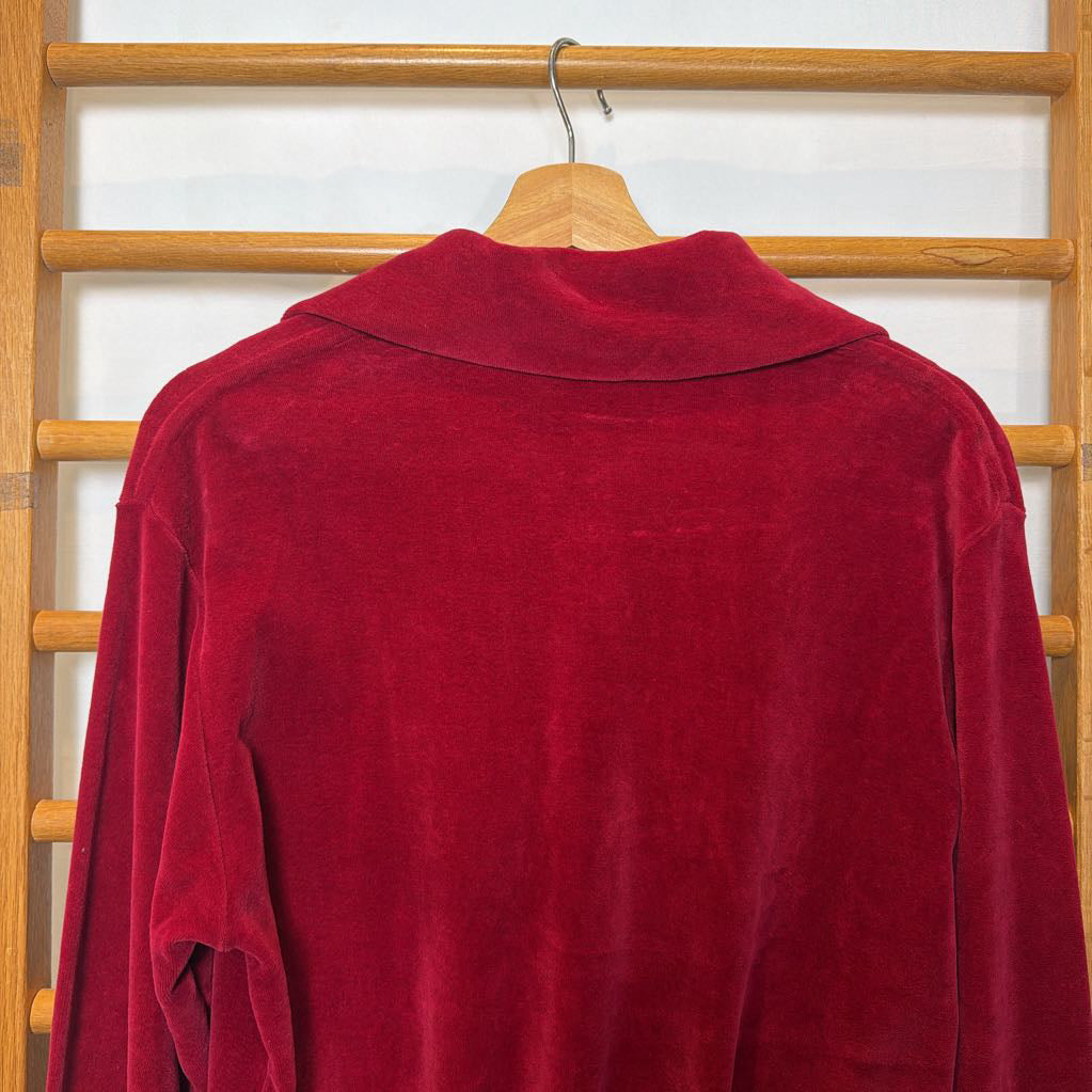 A red velour sweater on a wooden rack. 