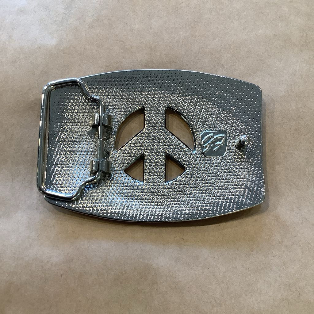 Metallic belt buckle with peace symbol design on a brown background