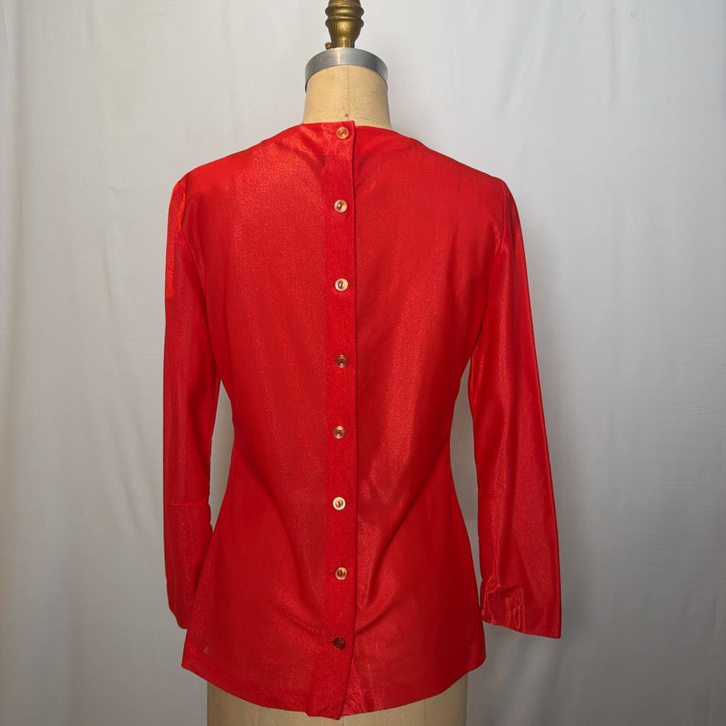 A shimmery red long sleeve blouse with a button up back on a mannequin in front of a white wall. 