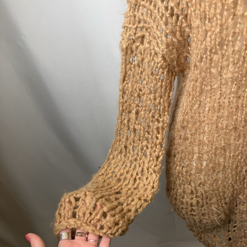 Close-up of a person wearing a brown knitted sweater with a plain background