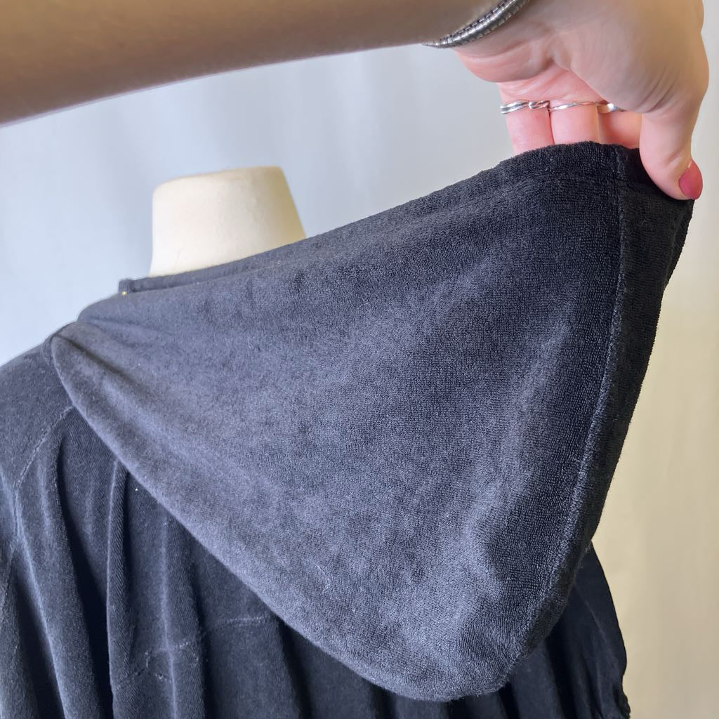 Person holding a black fabric on a mannequin against a neutral background