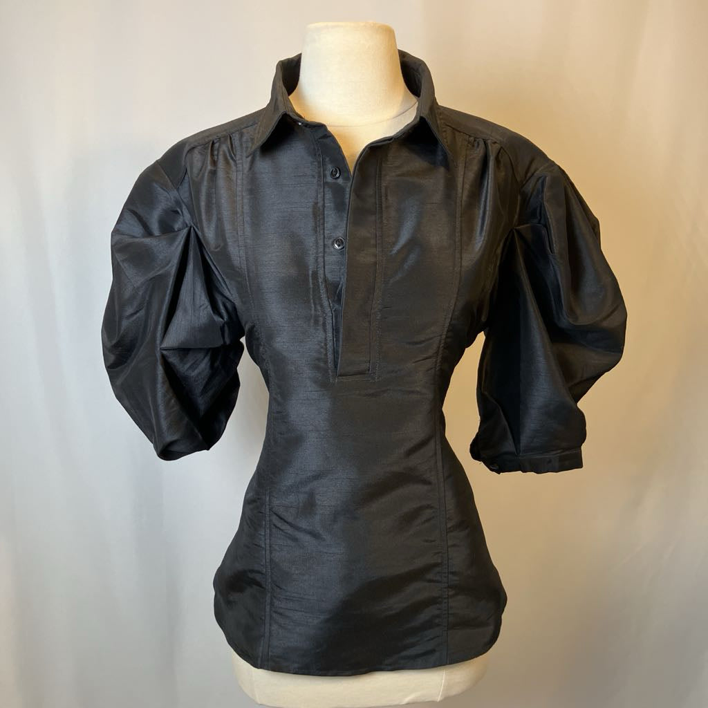 Black blouse on a mannequin against a plain background