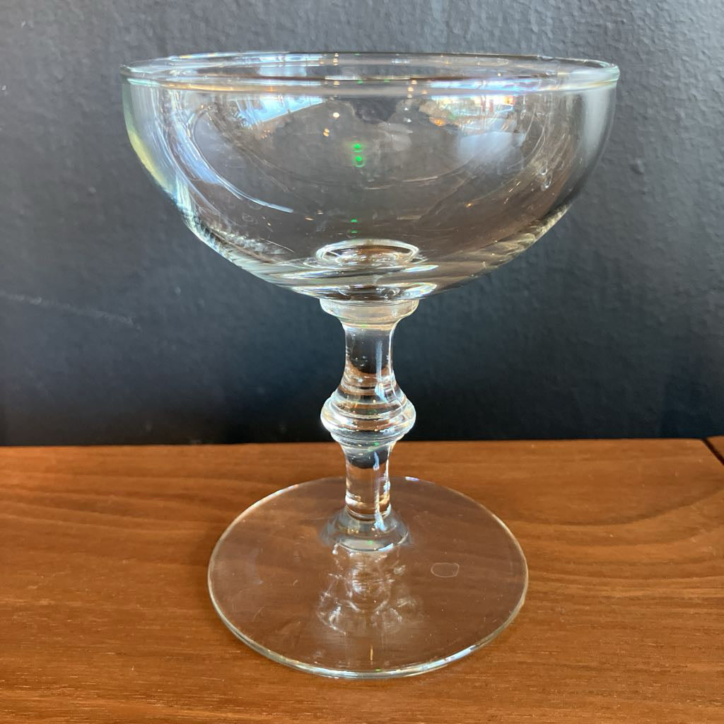 Clear glass coupe on a wooden surface with a dark background