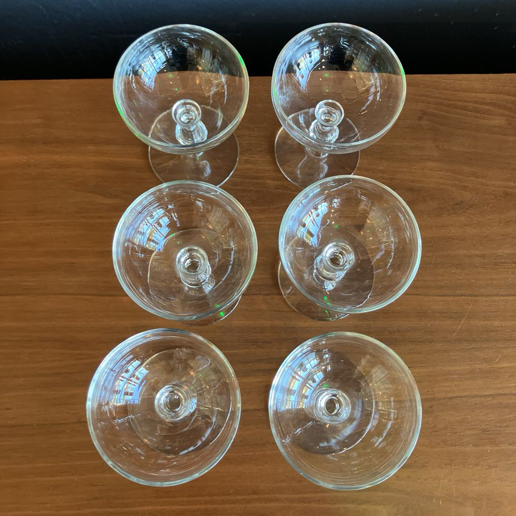 Set of six clear glass cocktail glasses on a wooden surface