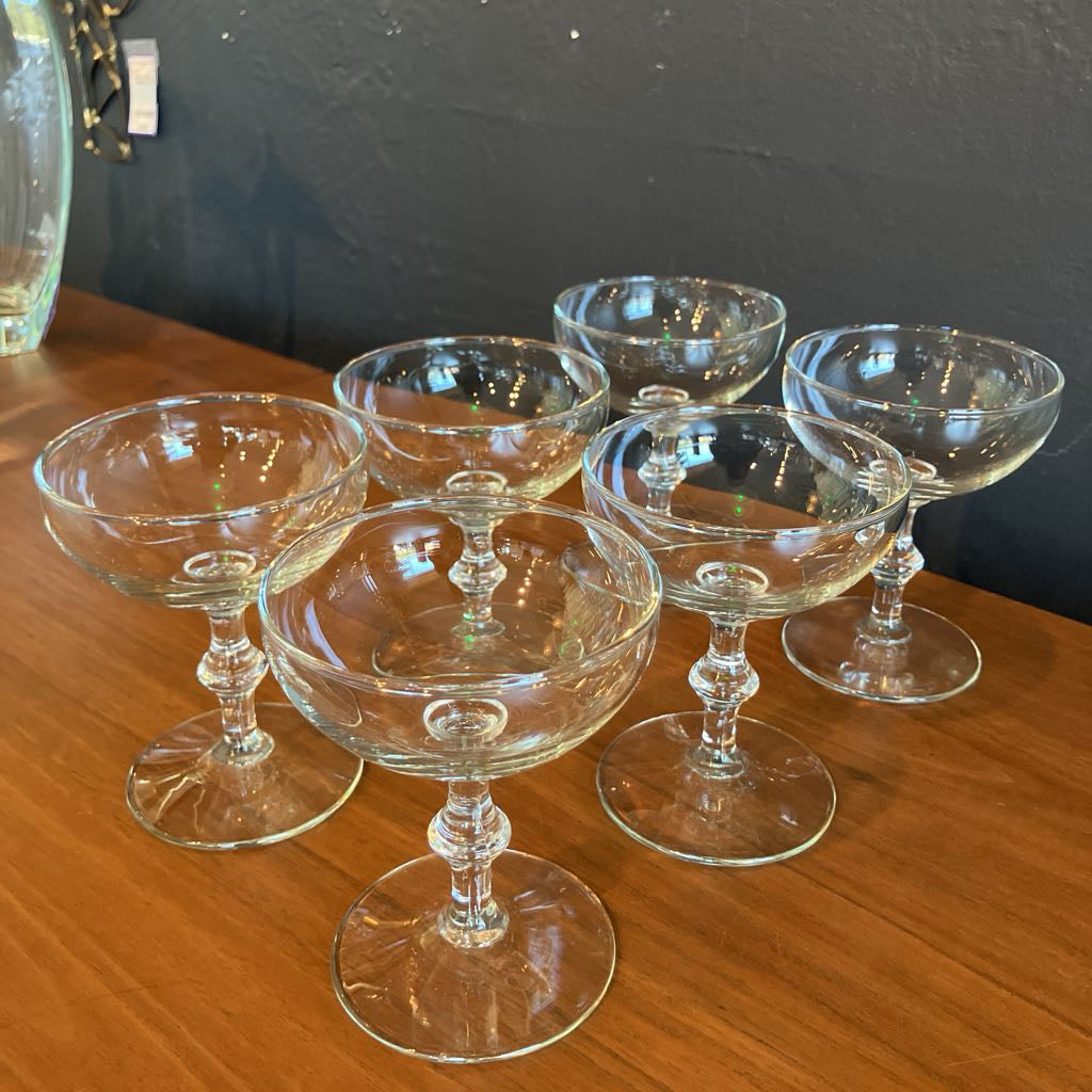 Set of clear glass coupes on a wooden surface with a dark background