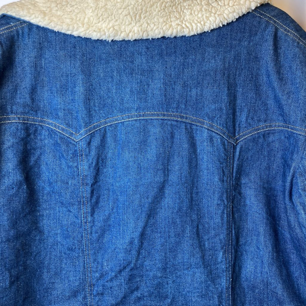 Blue denim jacket with white fleece lining on a wooden surface