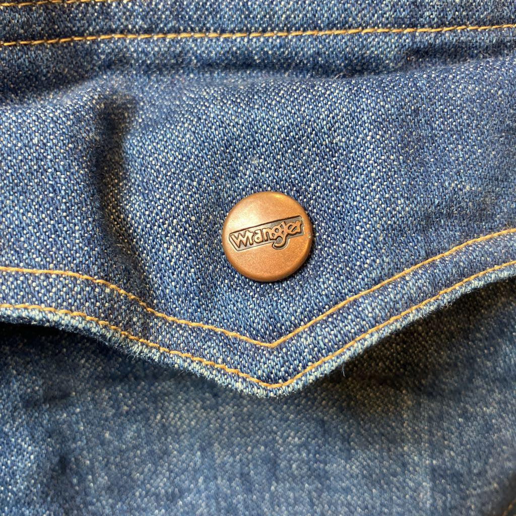 Close-up of a Wrangler button on blue denim fabric