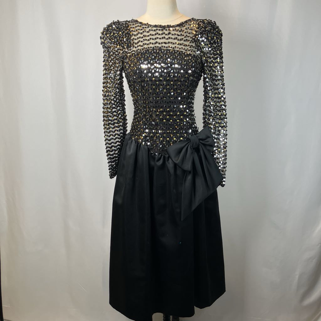Black dress with long sleeves and a bow on a mannequin against a plain background