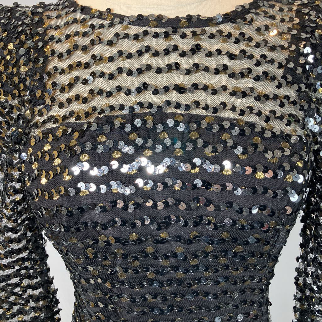 Close-up of a black sequined garment with gold accents on a white background