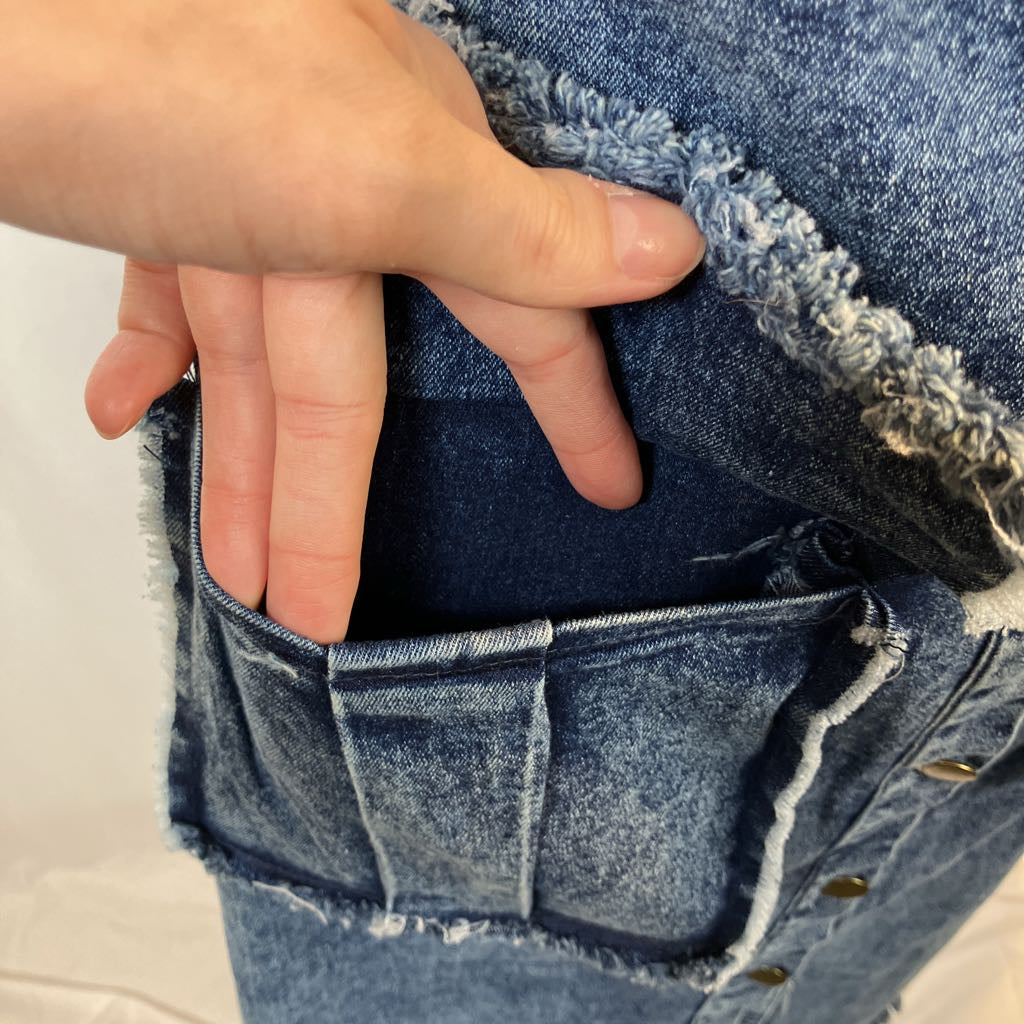 Close-up of a hand adjusting the waistband of blue jeans on a light background