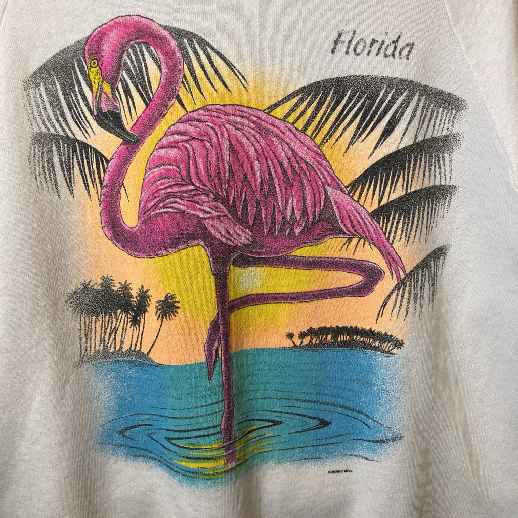 T-shirt with a pink flamingo design on a beach with palm trees and 'Florida' text.
