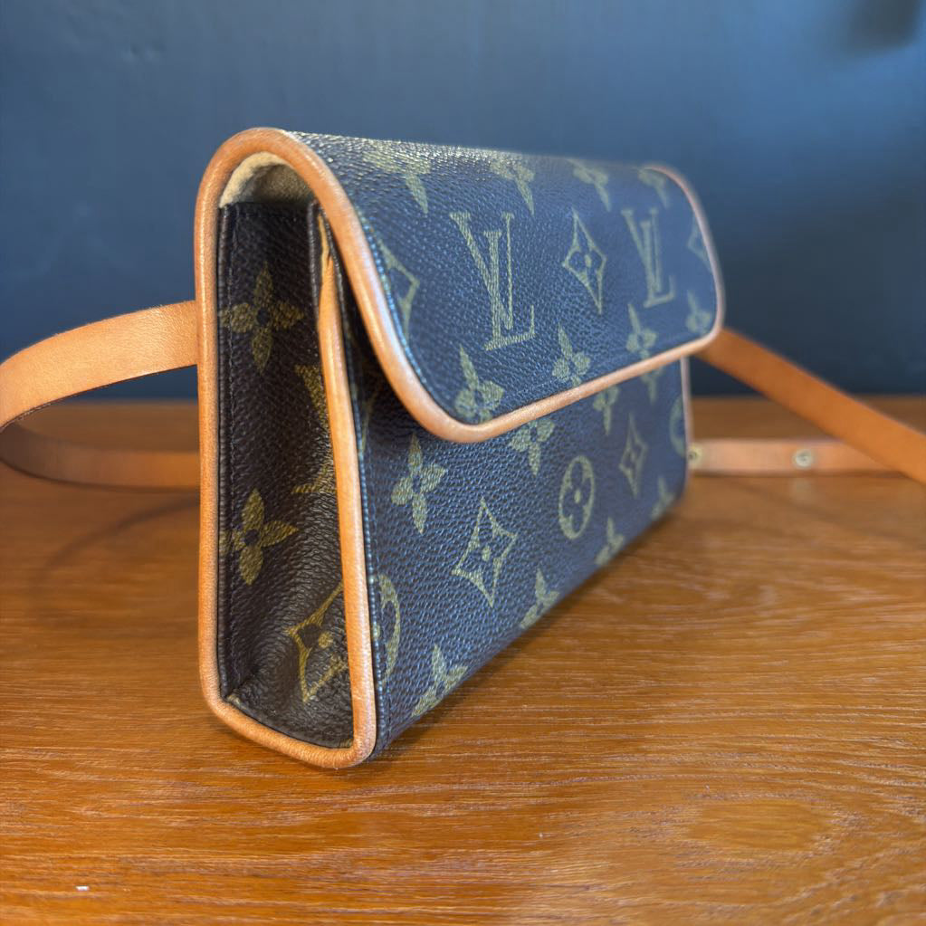 Blue handbag with brown leather strap on a wooden surface