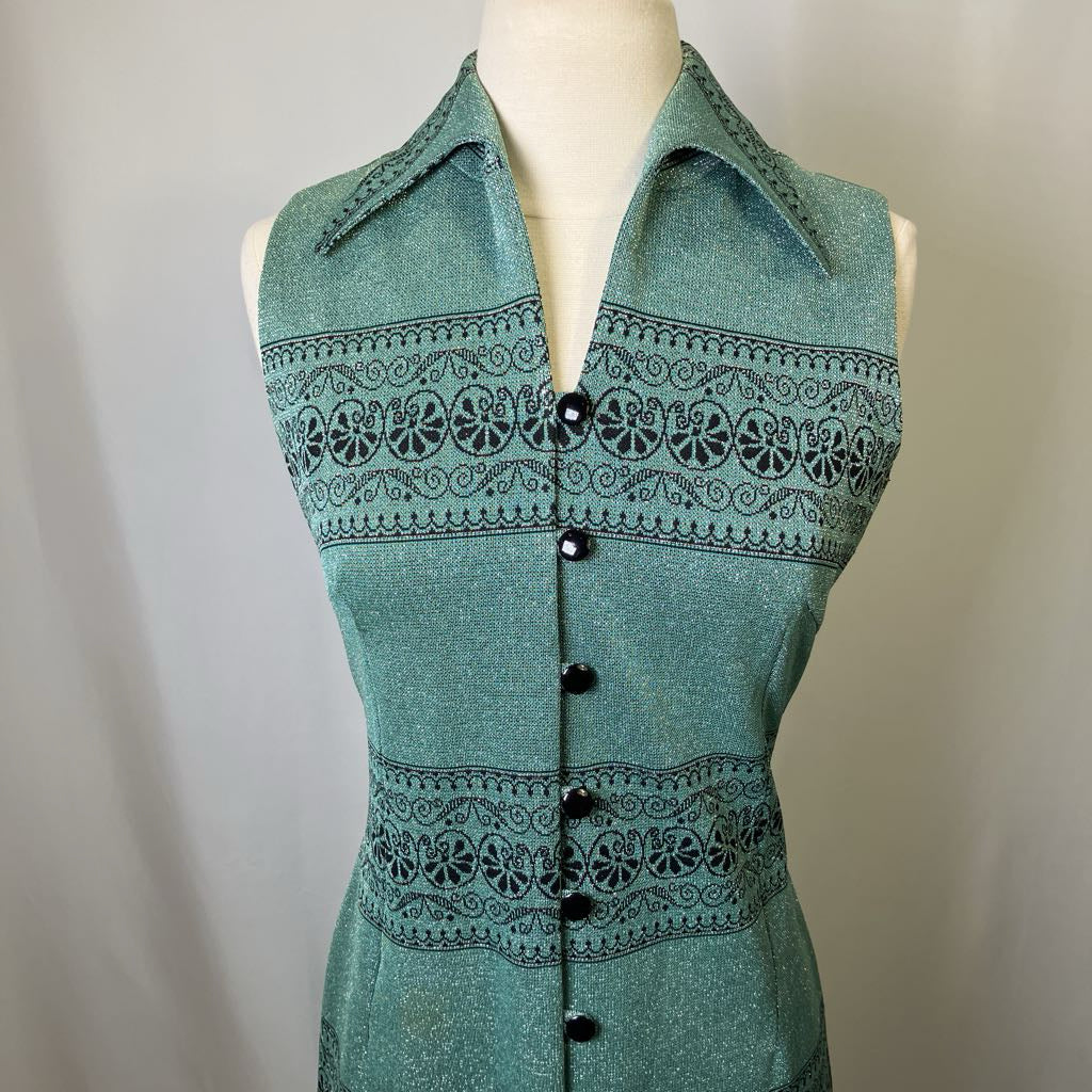 Green sleeveless top of dress with black pattern on a mannequin against a plain background