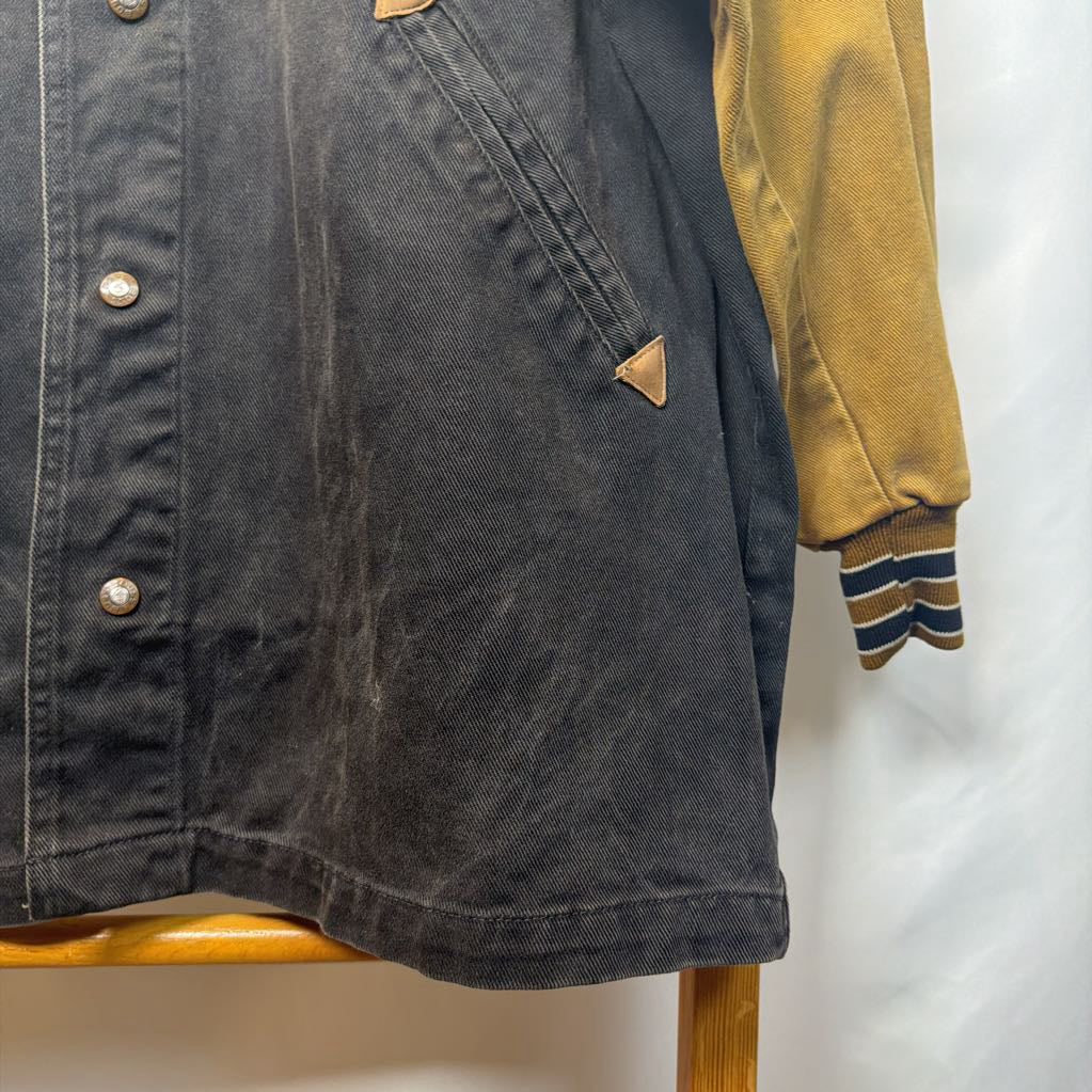 Dark denim jacket and mustard yellow shirt with striped sleeves on a wooden surface.