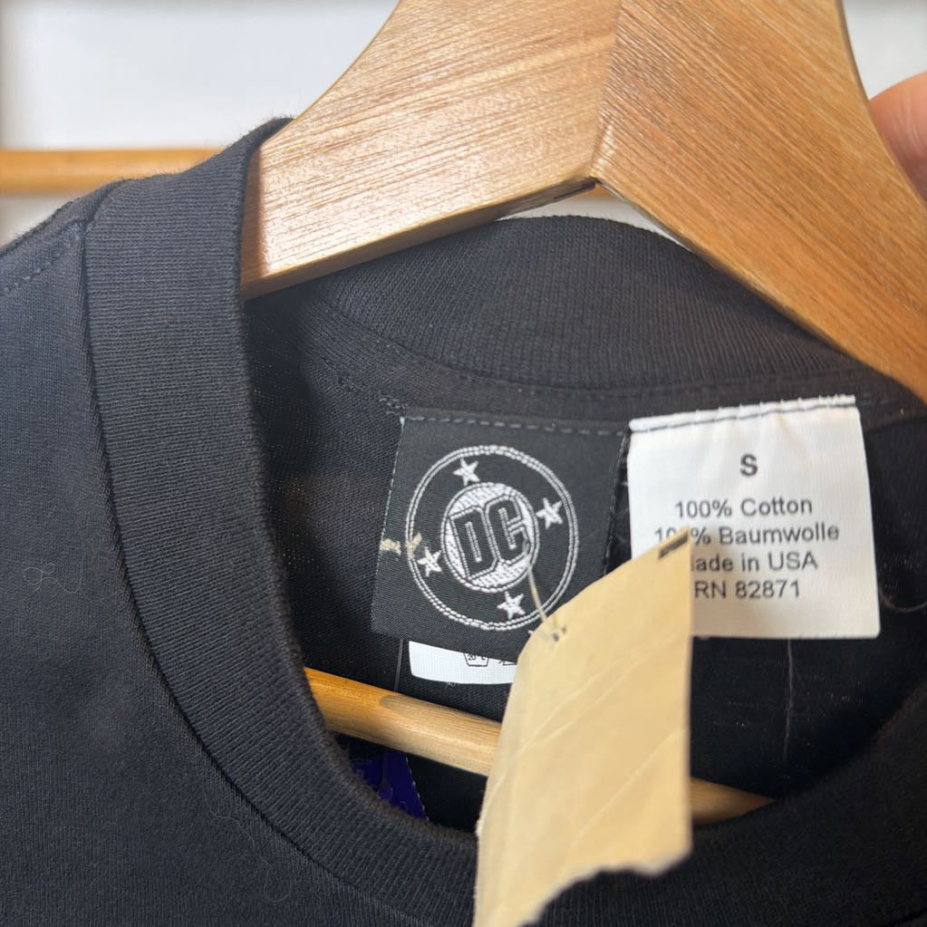 Black t-shirt with a brand label on a wooden hanger