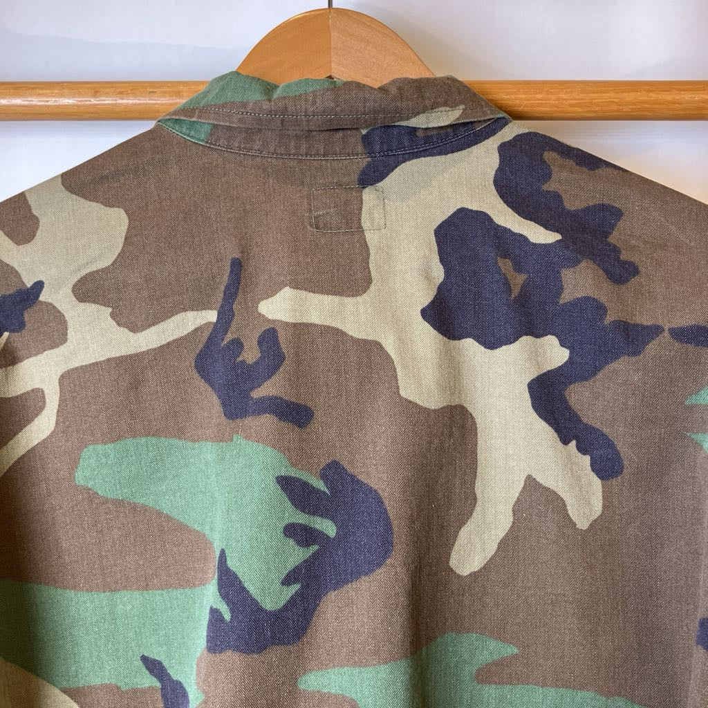 Camouflage-patterned jacket on a wooden rack against a white background