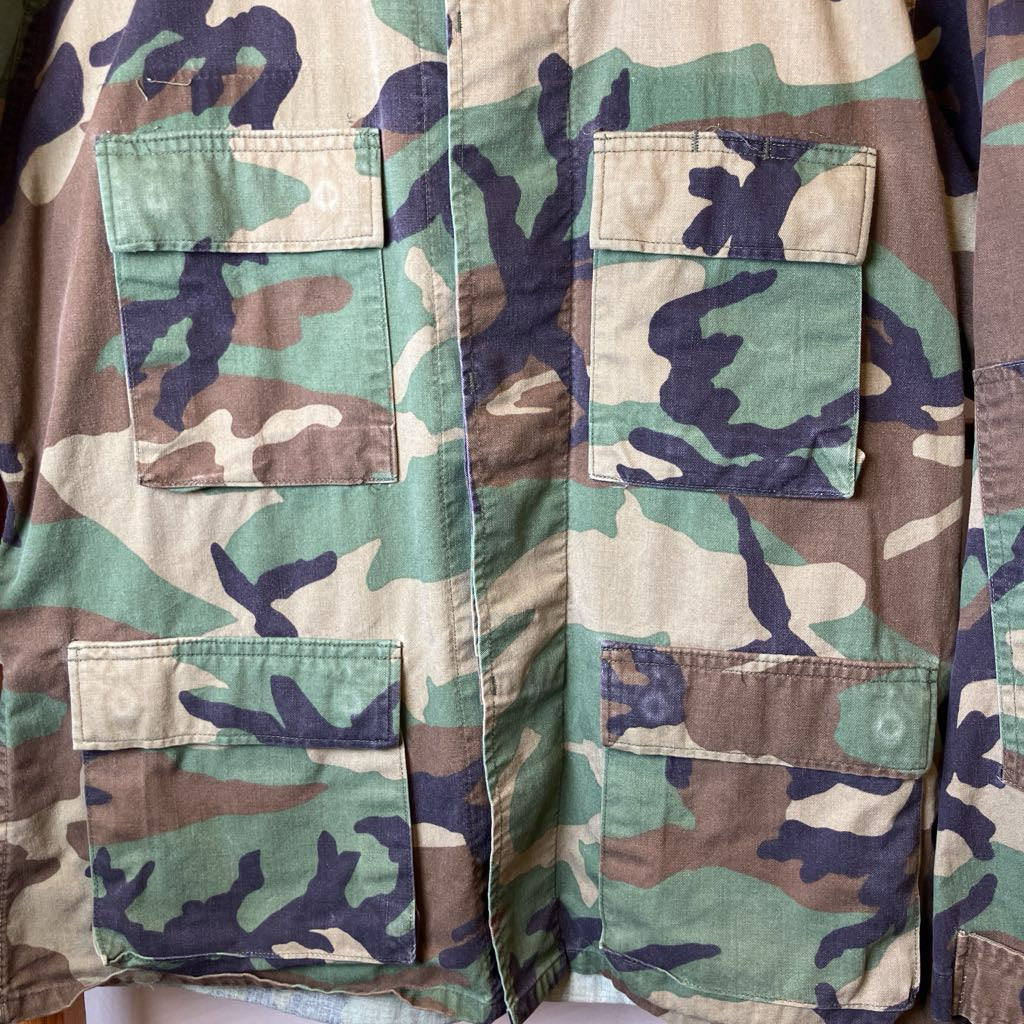 Camouflage jacket with multiple pockets on a plain background