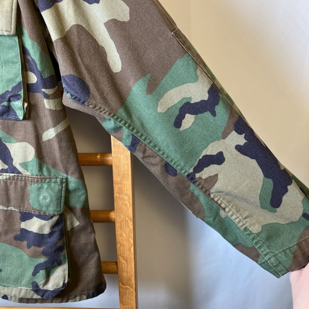 Camouflage jacket on a wooden rack with a neutral background