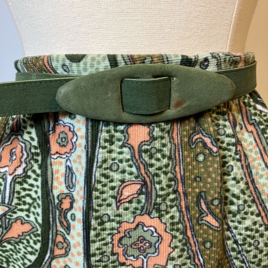 Patterned fabric with a green belt and buckle on a mannequin.