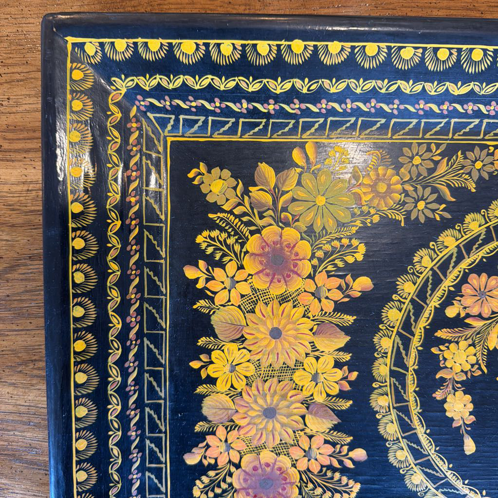 Decorative box with floral patterns and yellow accents on a wooden surface
