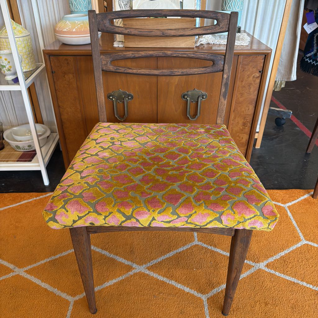 Wooden chair with a patterned cushion on an orange and white geometric rug.