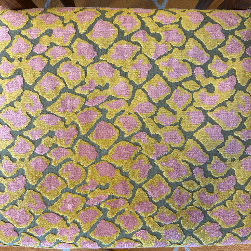 Fabric with pink and yellow geometric pattern on a wooden surface