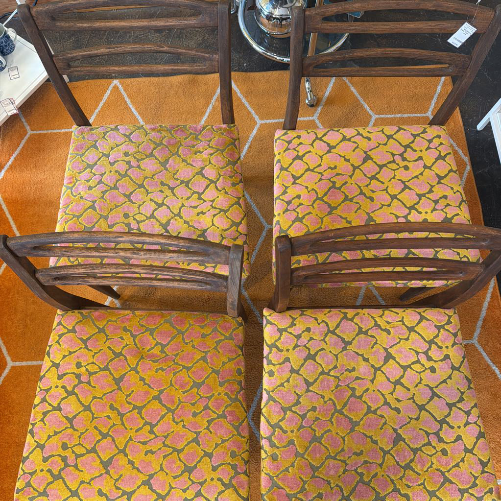 four wooden chairs with patterned cushions on a tiled floor.