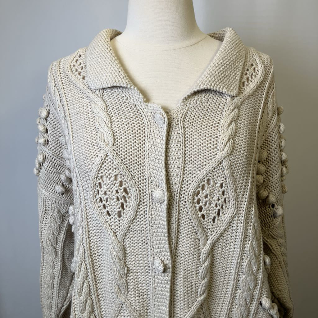 Knitted cardigan with intricate patterns on a mannequin against a neutral background