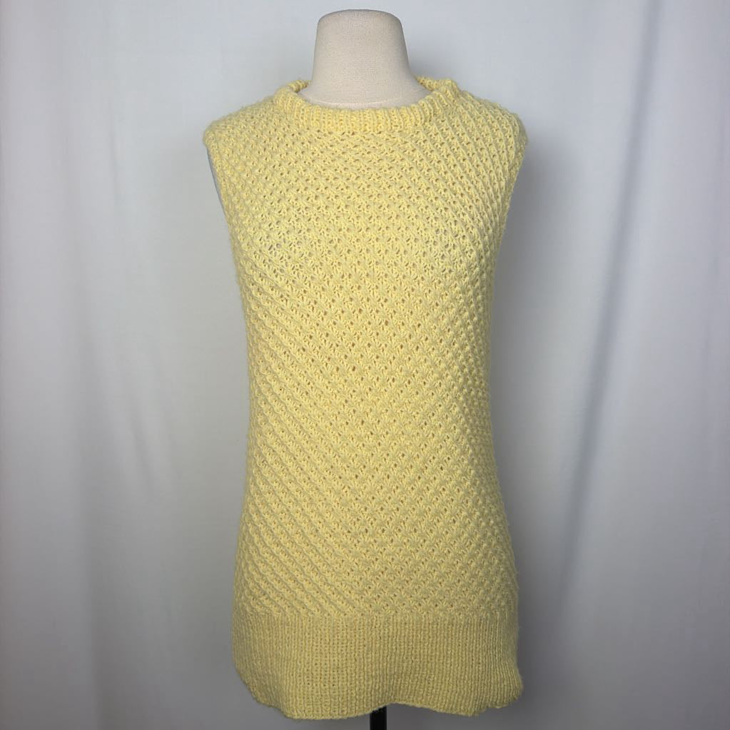 A pale yellow sleeveless knit sweater dress with a textured openwork pattern, displayed on a mannequin torso against a light gray fabric backdrop.