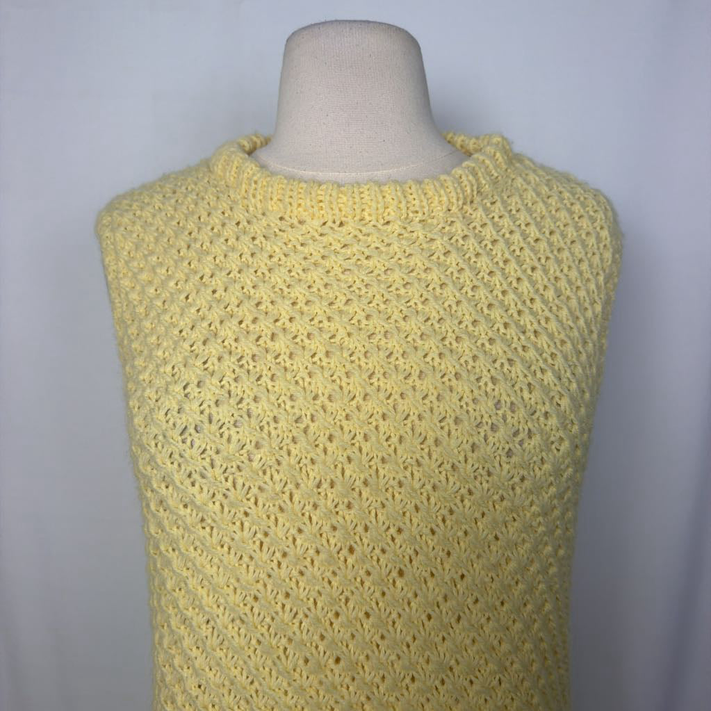 A pale yellow sleeveless knit top with a textured openwork pattern, displayed on a cream-colored dress form mannequin against a light gray background.