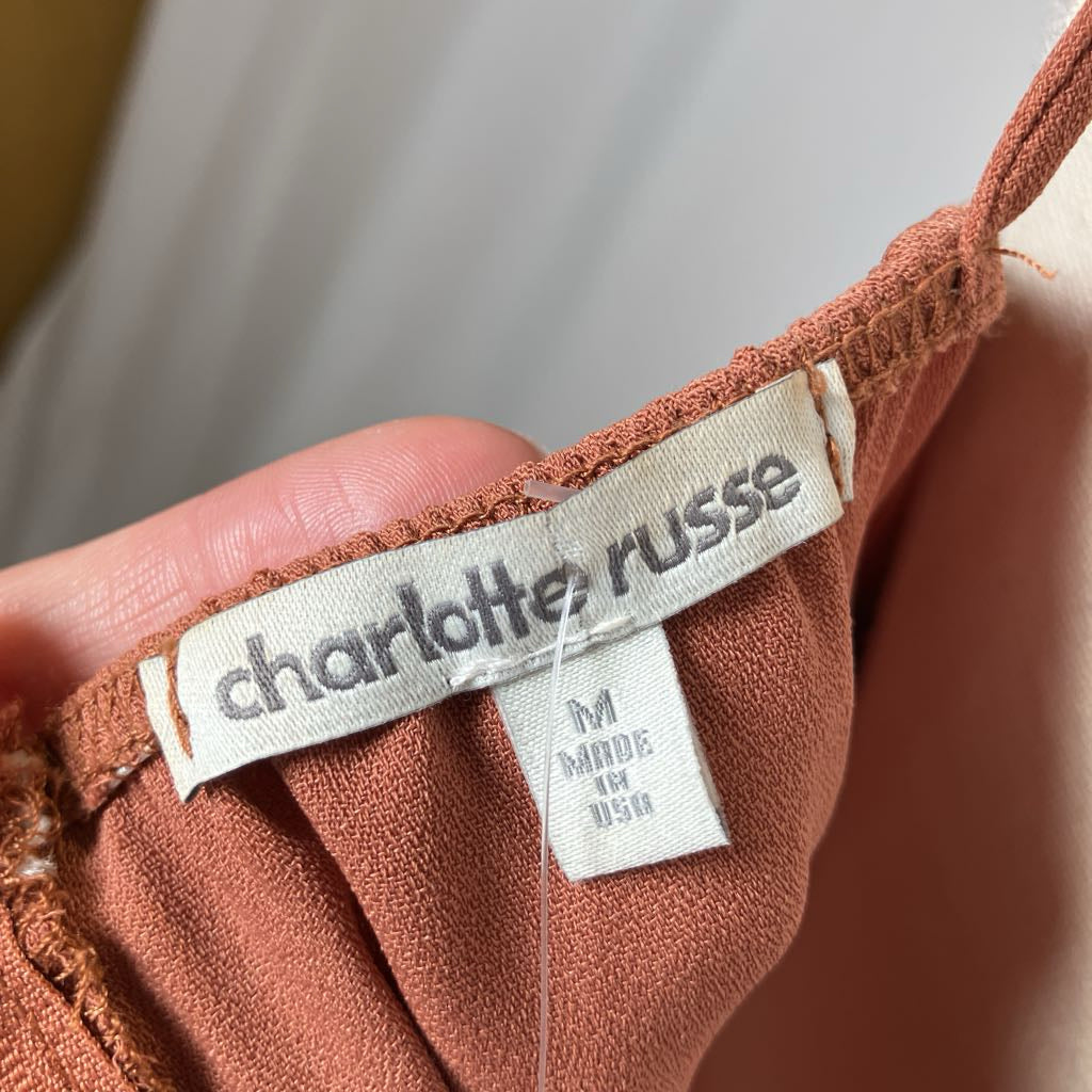 Close-up of a 'Charlotte Russe' label on a brown fabric product.