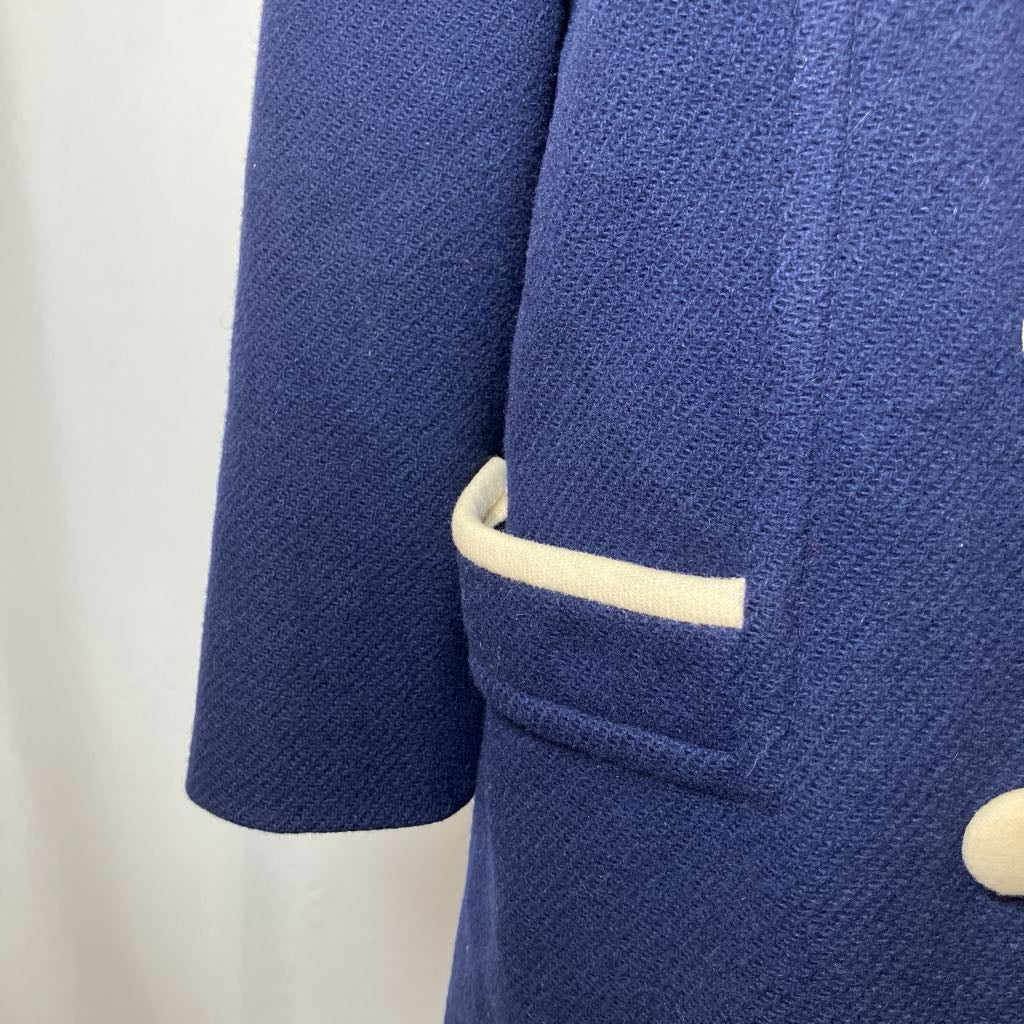 Close-up of a blue textured jacket with a white button on a light background