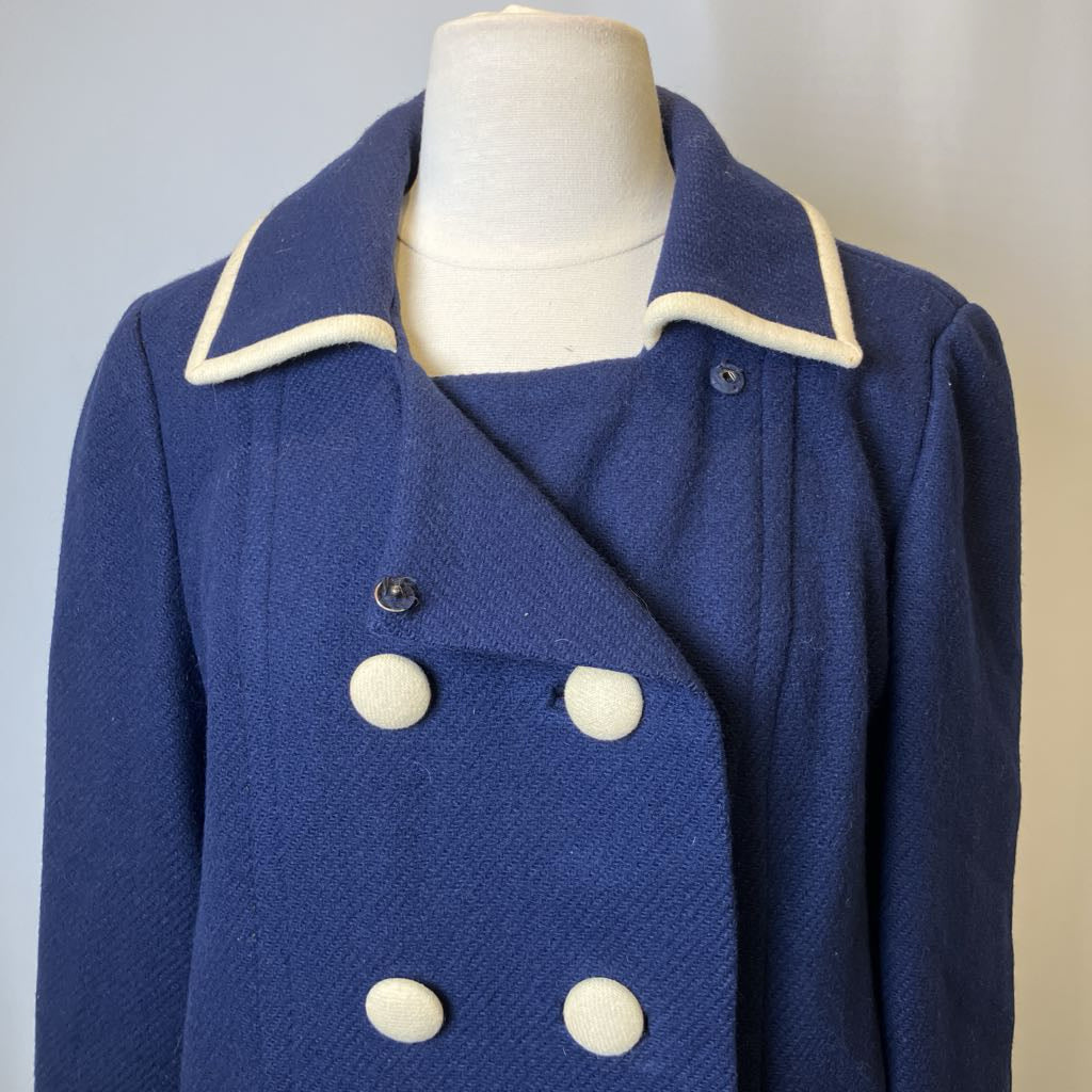 Blue coat with white buttons on a mannequin against a plain background