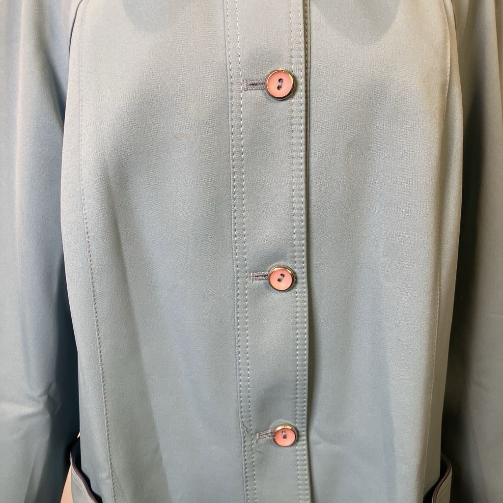 Close-up of a light gray jacket with buttons on a neutral background