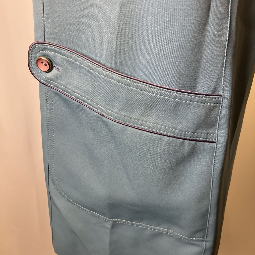 Close-up of a gray jacket pocket with a button on a beige background