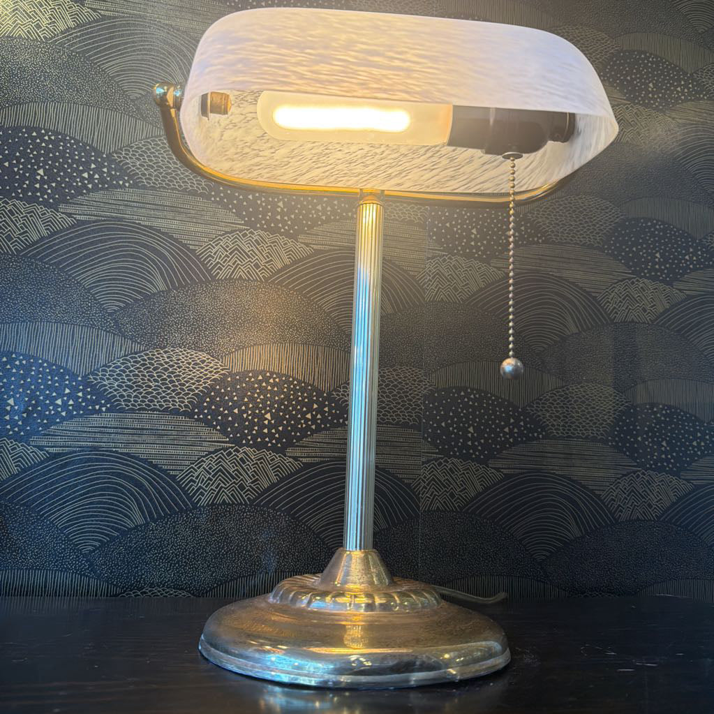 Table lamp with a textured white shade on a dark surface with patterned background