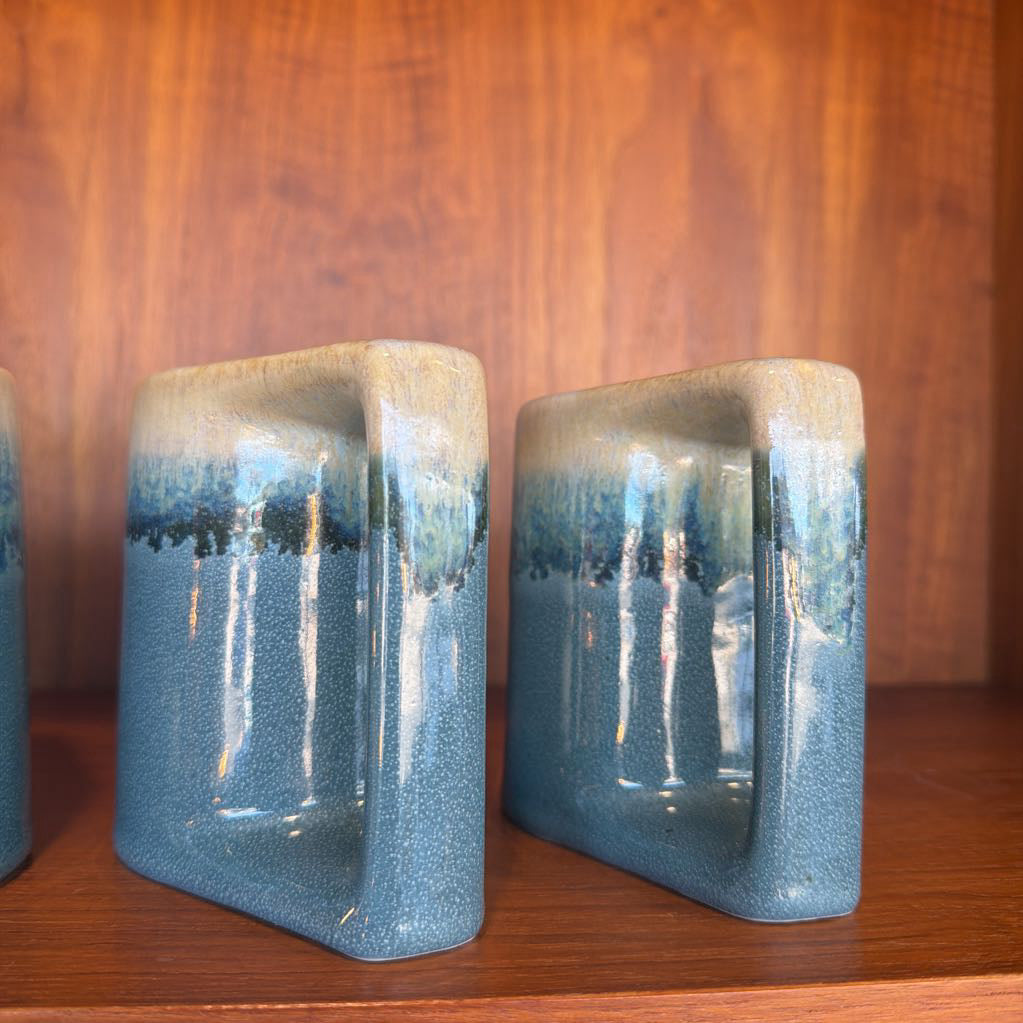 Two blue ceramic bookends on a wooden surface with a wooden background