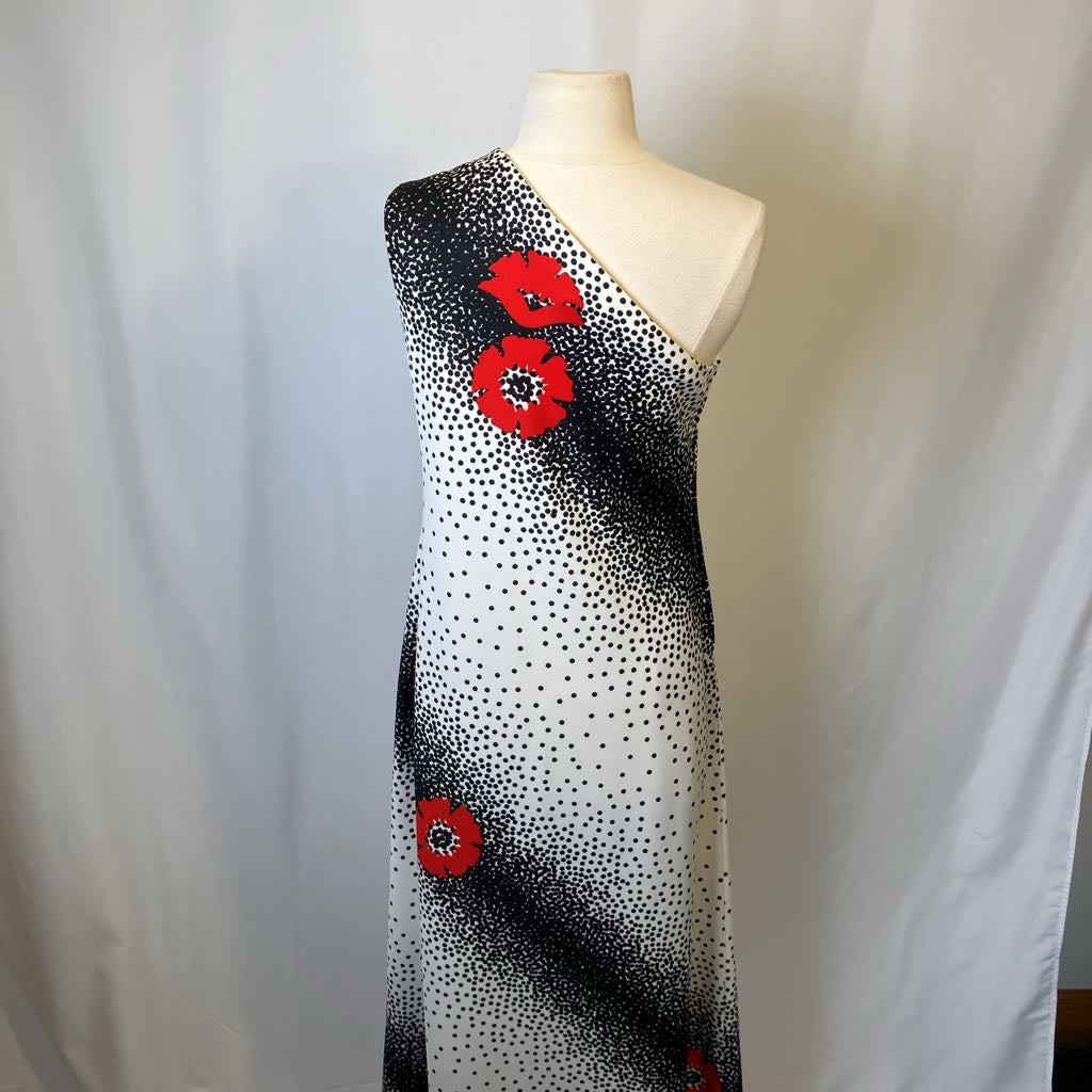 Dress with black dot pattern and red floral accents on a mannequin against a white background