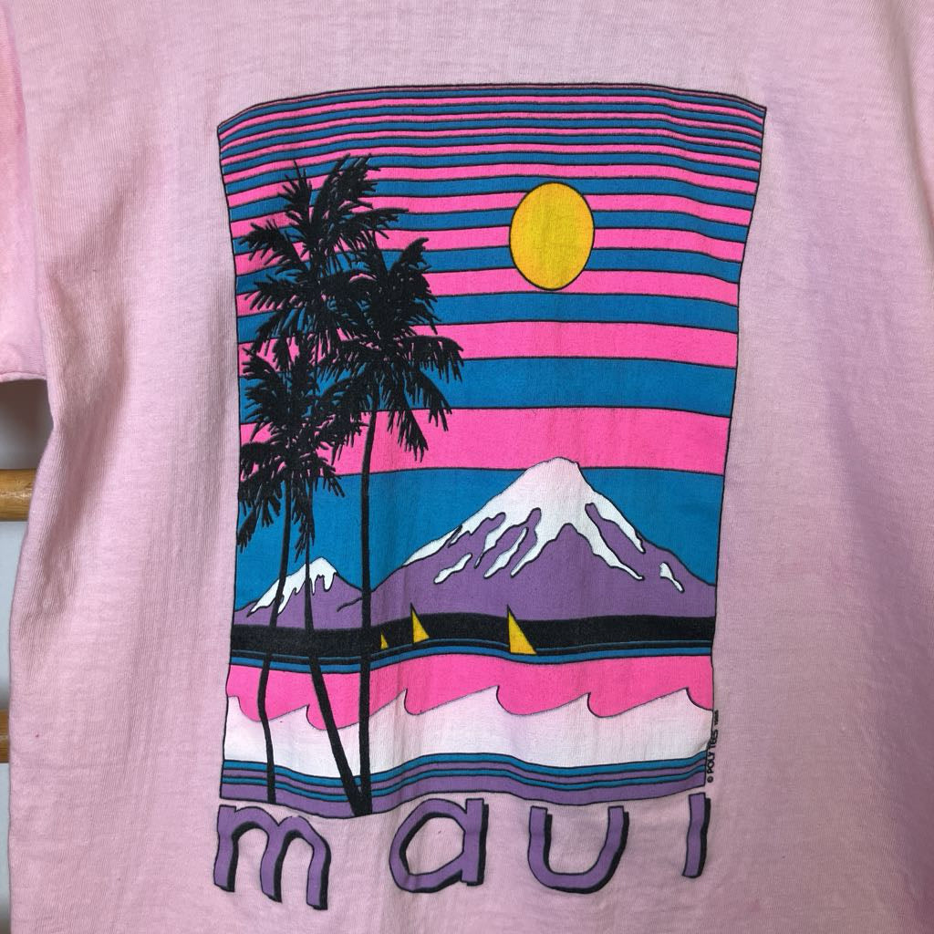 T-shirt with a colorful design of a sunset, palm tree, and mountain on a pink background.