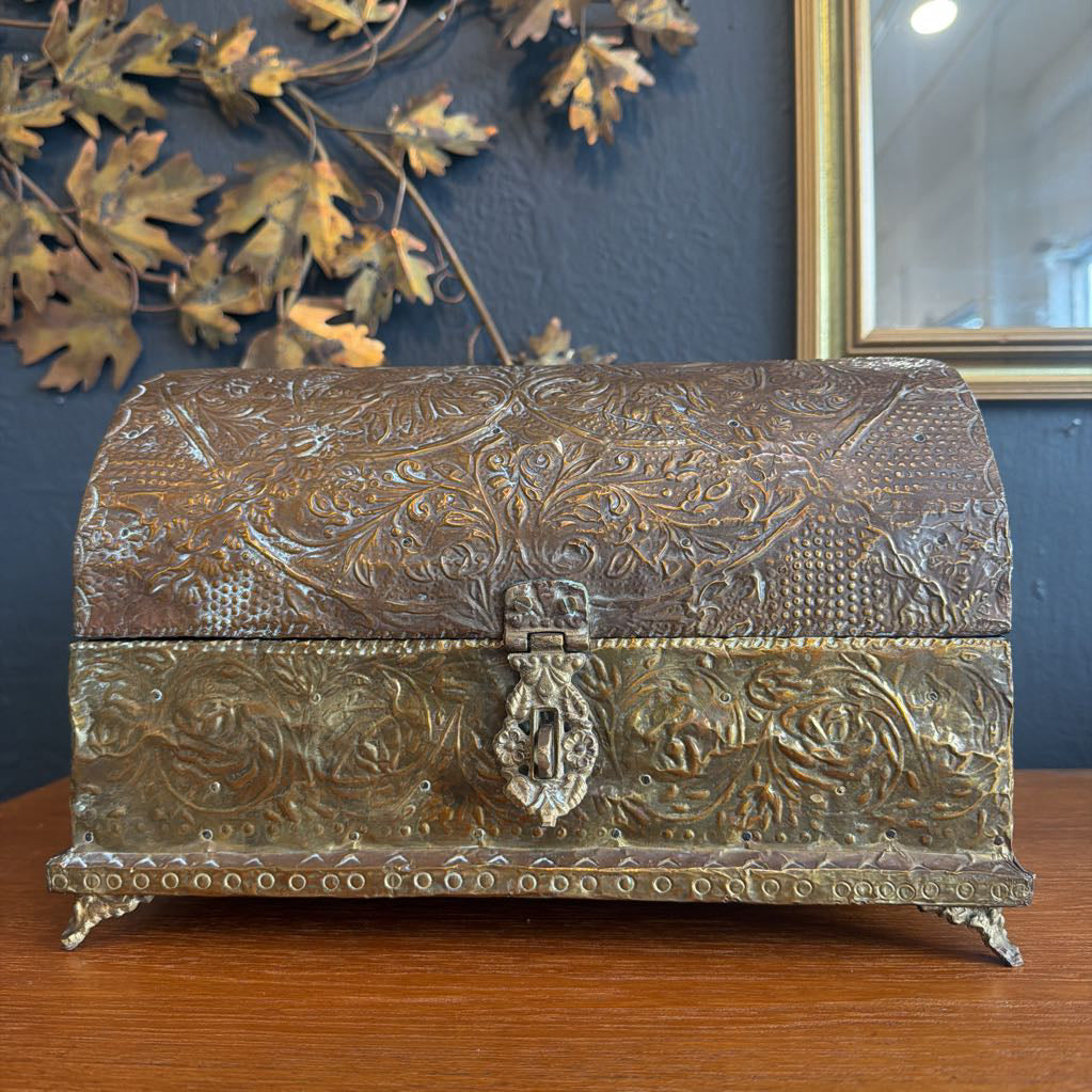 Decorative metal box with intricate designs on a wooden surface.