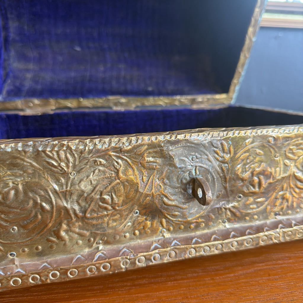 Decorative metal object with intricate designs on a wooden surface